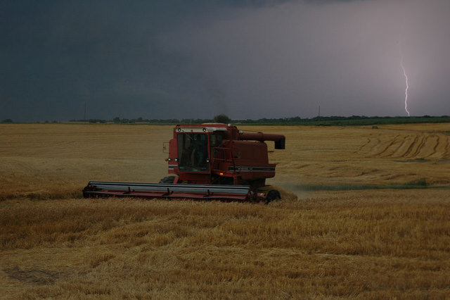 A lightning bolt strikes behind a combine trying to finish wheat harvest